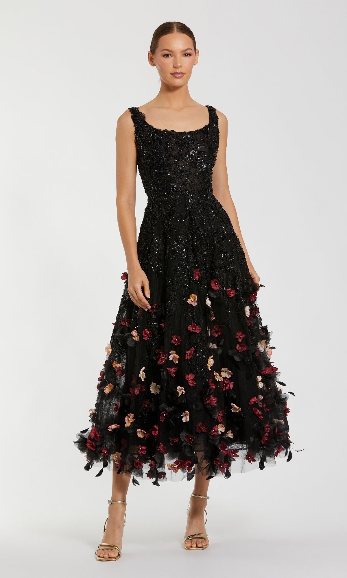 A woman wears the Mac Duggal 21085 A-Line Wedding Guest Dress, a sleeveless black mid-length style with sequin floral appliques and 3D red blossoms, paired with strappy heels.